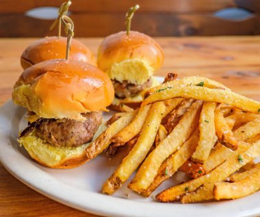 The small hamburgers with french fries on the plate