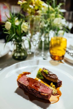A vertical shot of a fine dinner in a Michelin restaurant in London with flowers in the background