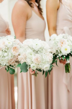 A vertical closeup of bridesmaids holding bouquets of roses