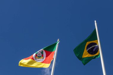 Brezilya ve Rio Grande do Sul eyalet bayrakları güneşli bir günde rüzgarda sallanıyor. Mavi gökyüzü arkaplanı