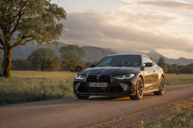 Günbatımında modern bir BMW M4 'ün, Dağ v. lüks spor arabalı görüntüsü birçok sürücünün hayalindeki arabadır.