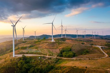 The windmill turbines in a field at sunset