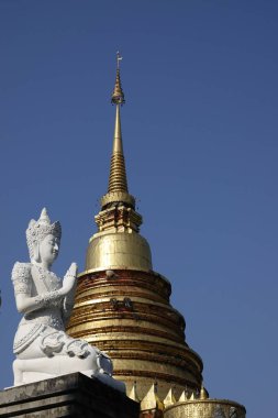 A vertical shot of a white Buddha statue in a blue sky background