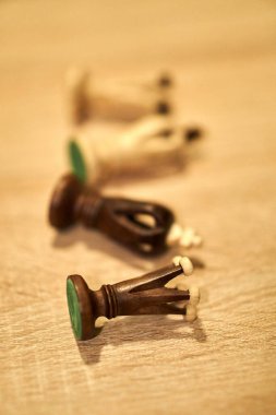 A selective focus shot of chess pieces on a wooden surface with blurred background