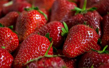 Markette satışta olan olgun kırmızı çileklerin yakın çekimi.