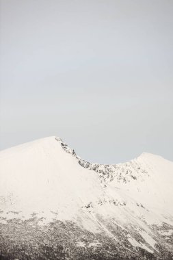 Her tarafı karla kaplı yüksek bir dağın manzaralı bir görüntüsü.