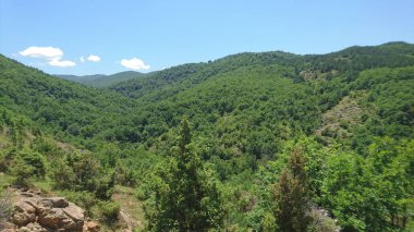Arkasında mavi gökyüzü olan dağlık bir manzara.