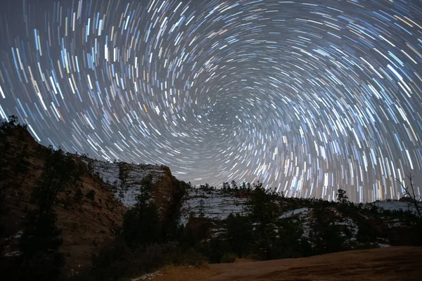 the Sky with a trail of circumpolar stars revolving on the polar star with the tree silhouettes view