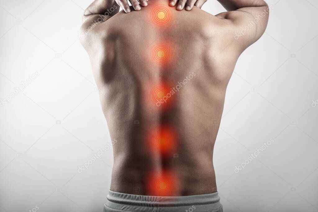 A muscular man suffering from spine injury, backache highlighted in red spot mark in gray background.