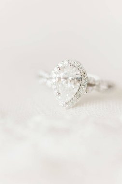 Beyaz arkaplandaki elmas nişan yüzüğünün dikey yakın çekimi.