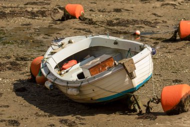 Boş bir beyaz balıkçı teknesi, dalgaların çekildiği sahilde turuncu şamandıralarla mahsur kalmış.