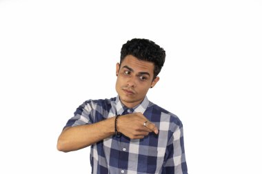 Beyaz bir arkaplanı işaret eden ciddi bir ifadeyle genç bir İspanyol erkek.