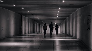 Metro istasyonunda yürüyen insanların gri tonlu bir görüntüsü.