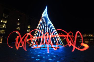 Aydınlatılmış bir sanat enstalasyonunun etrafındaki kırmızı ışık dalgalarının uzun pozlama görüntüsü