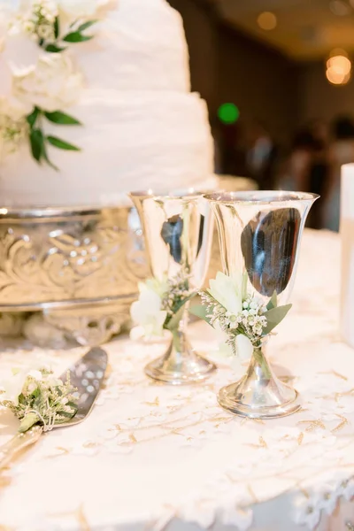 A selective focus shot of metallic glasses on the wedding table around the cake