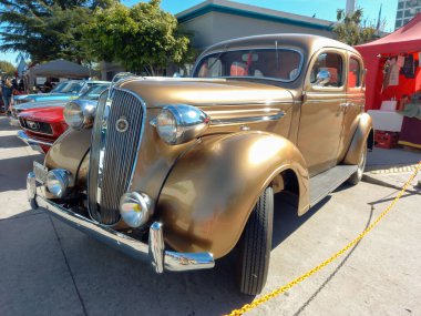 Eski altın rengi Plymouth dört kapılı, hızlı arka sedan 1938 model, sokağa park edilmiş. Expo Fierro 2022 Klasik araba şovu.