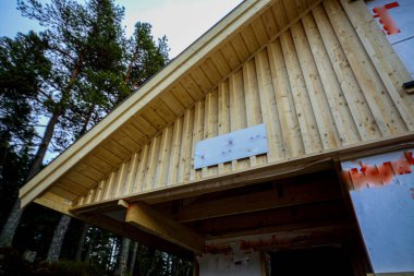 Uzun ağaçlara karşı ahşap bir binanın alçak açılı görüntüsü.