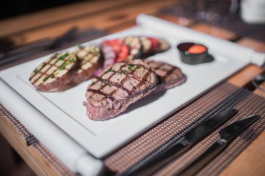 Kızarmış patates, domates ve soğanlı bir tabak et.