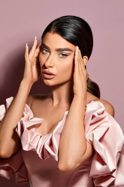 Omuzları açık, pembe arka planı olan siyah saçlı, beyaz bir kızın dikey portresi.