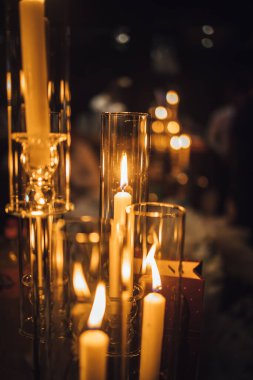 Şeffaf bir şamdanda yanan bir mumun dikey görüntüsü.