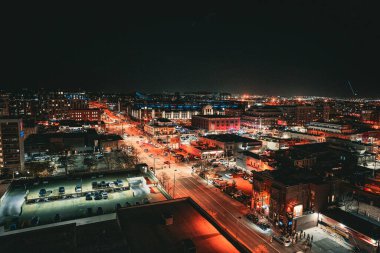 Geceleri fenerlerle ve trafik ışıklarıyla aydınlatılan bir şehir manzarasının hava görüntüsü.