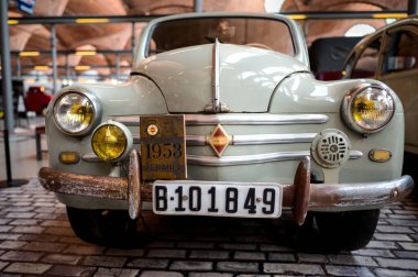A Renault 1953 front detailed view inside an exhibition with an orange background from the building roof.