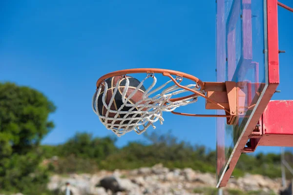 basketball ball on an outdoor basketball court, after basketball player shot