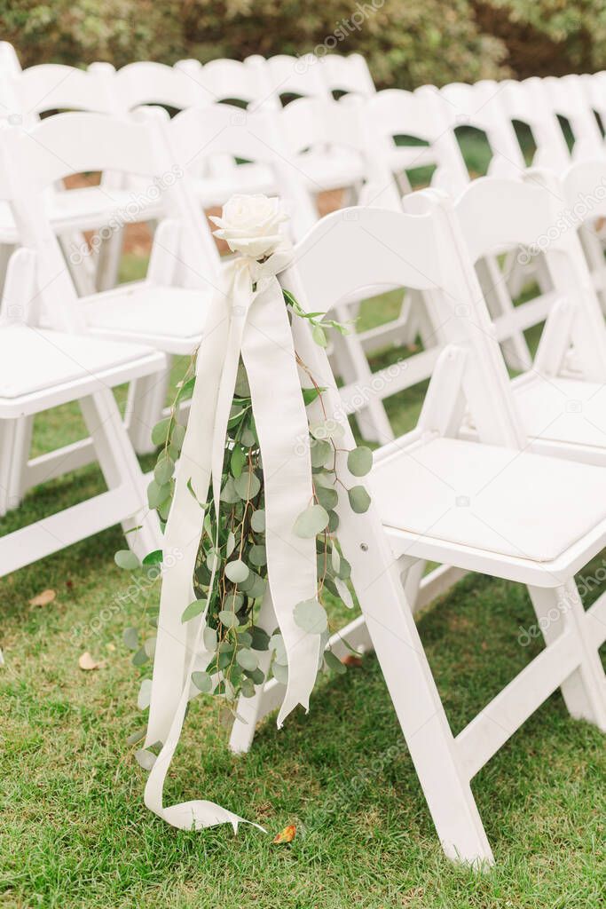 The outdoors chairs decorated with flowers for the wedding