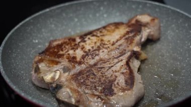 Tavada kızaran T-Bone bifteğinin yakın çekimi.