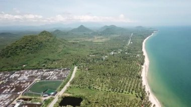 An aerial footage of green forests and hills in Thailand surrounded by the sea