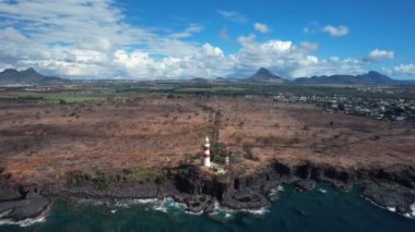 An aerial footage of a lighthouse near the ocean in cloudy sky background