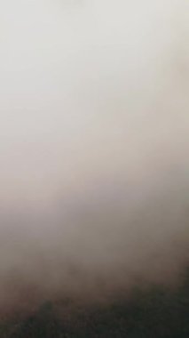 A vertical aerial shot of clouds floating over rural hills