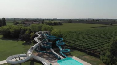 A bird's eye view of swimming pool splashdowns surrounded by green fields and trees in summer