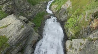 A drone shot over a beautiful waterfall flowing between green rocky mountains