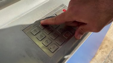 Male's hand pressing the keys of an ATM machine outdoors