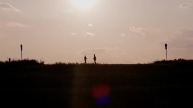 The silhouettes of people walking on the riverbank of Edogawa river