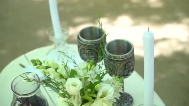 An outdoor table with flowers, candles, and vintage glasses