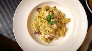 A top view of pasta with cheese on a white plate on a table