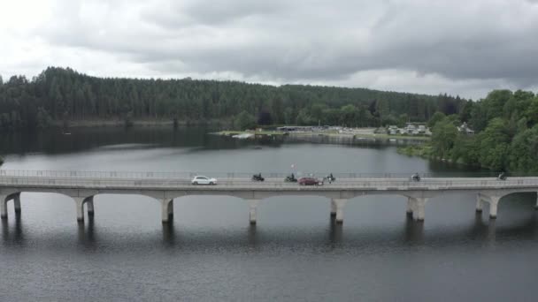 在一个村庄的湖面上方的桥路上 一部关于摩托车在桥路上疾驰的高角度无人驾驶镜头 — 图库视频影像