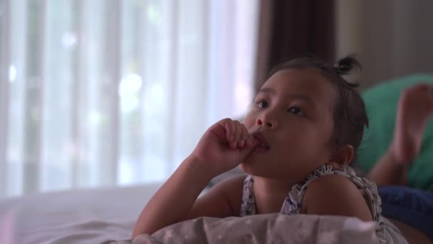 可愛いです東南アジアの子供かむ彼女の指でテレビを見ながら — ストック動画