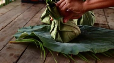 Close up of hands unpacking khmer food takeaway packed in eco-friendly lotus leaves in Siem Reap, Cambodia