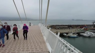 An HD footage of people walking on a bridge at the pier in Tamsui fisherman's wharf