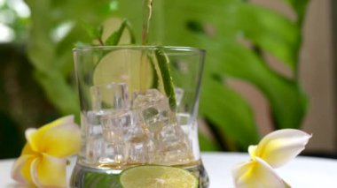 A closeup of a refreshing tropical drink poured into a glass with ice