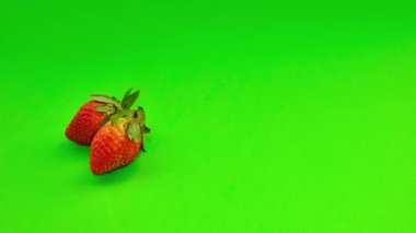 Fresh strawberries, pears, and oranges on a green background
