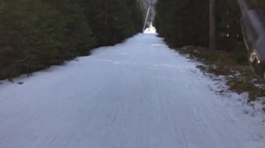 A POV of a snowboard or ski rider on a drag lift