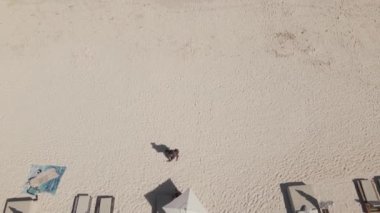 A drone view of sea waves covering a bright sandy beach.
