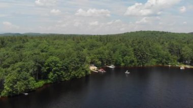 A drone flies towards a cabin and boat dock on a lake