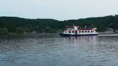 A steamboat sailing on a lake with a forest background.