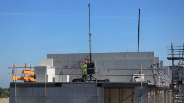 Supporting home wall being build by construction workers with small crane