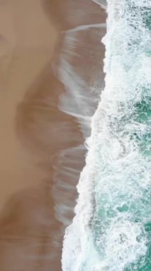 Okyanus turkuazının dikey drone görüntüsü kayalara değen köpük dalgaları, Ericeira, Portekiz